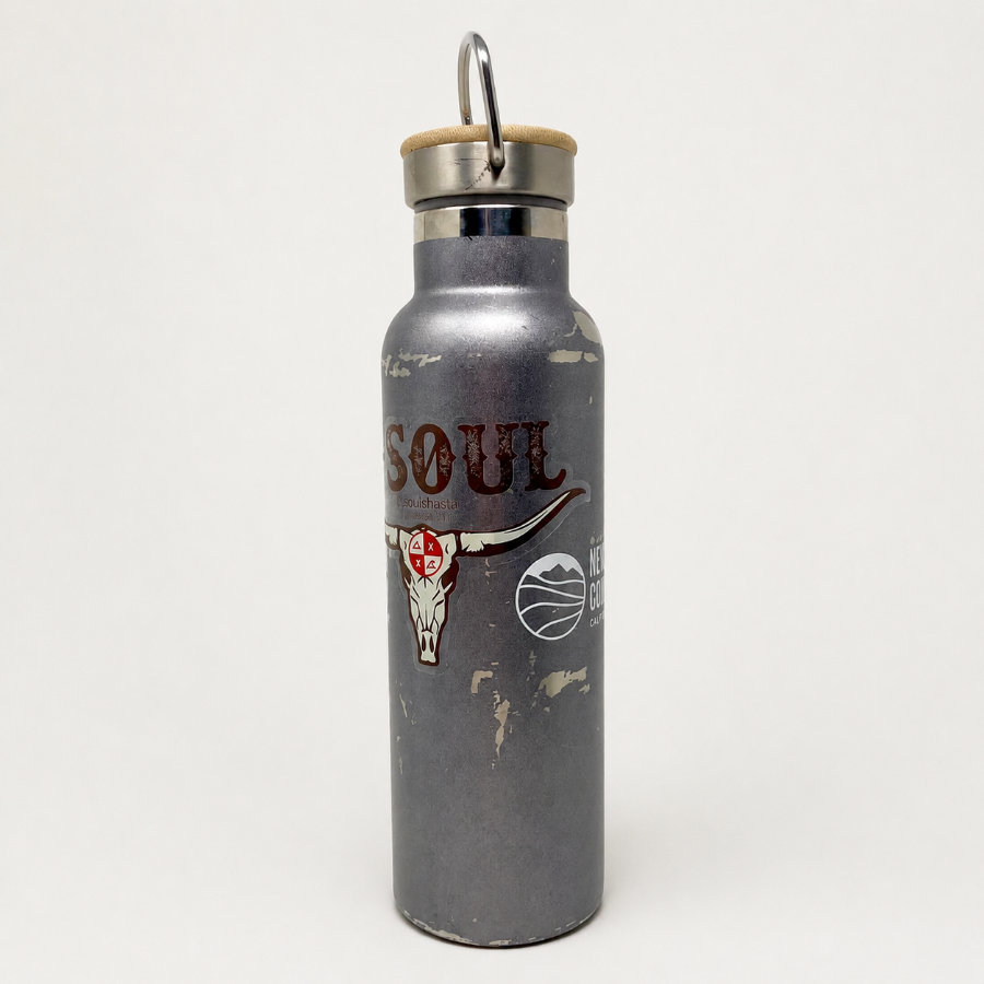 Clear sticker applied to a gray water bottle, showing a custom longhorn skull design with a transparent background.
