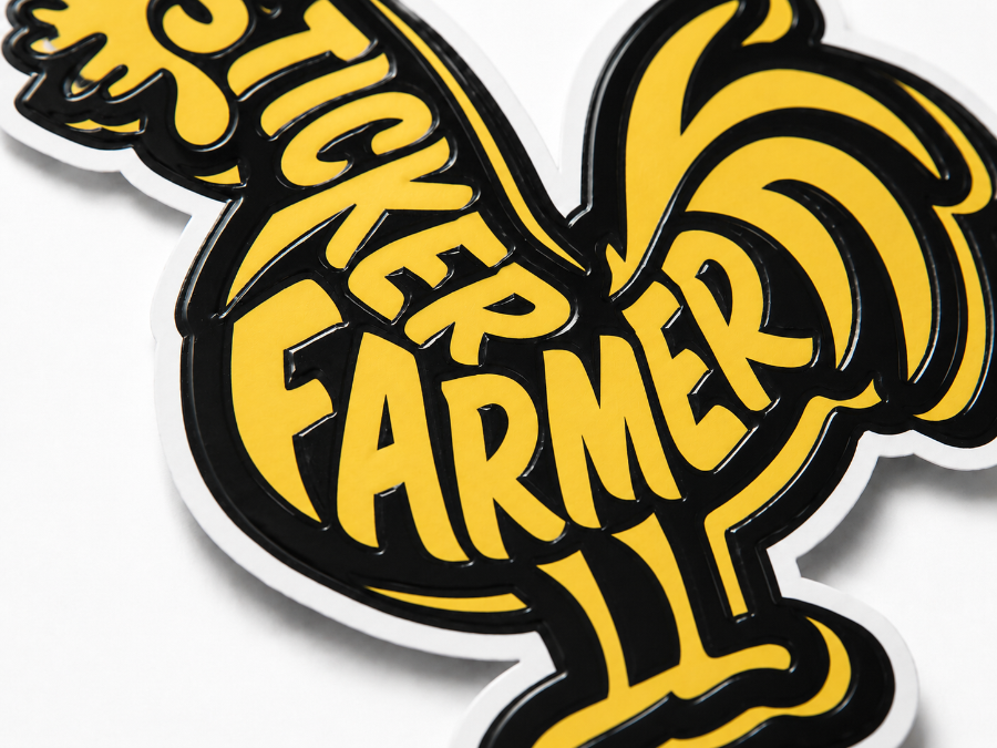 Close-up of a die-cut Sticker Farmer rooster sticker with bold yellow lettering and a shiny 1-pass spot UV finish on the black areas.