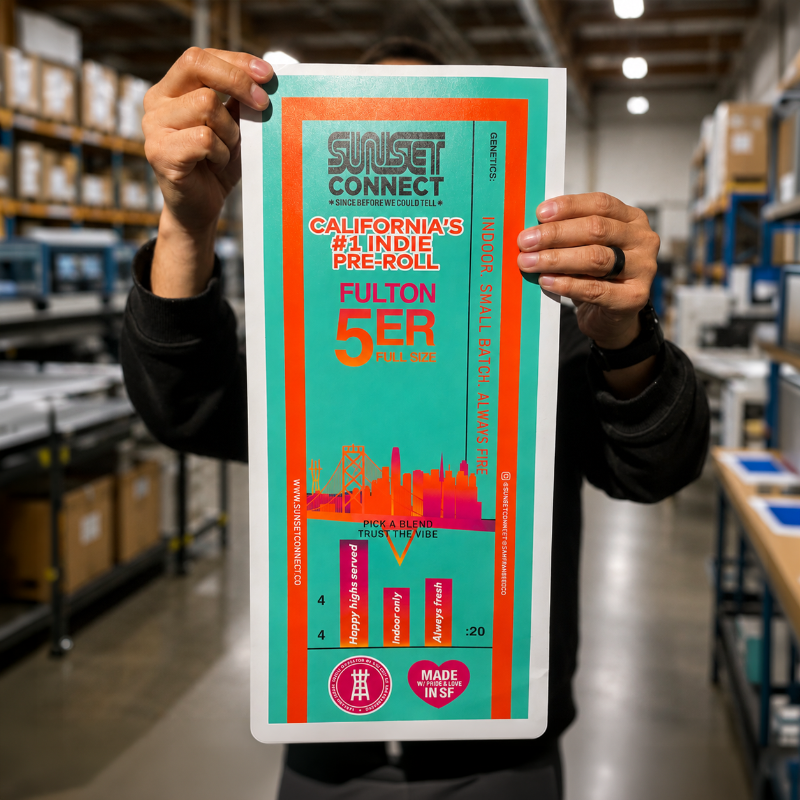 Large custom vinyl label with a colorful teal and orange product packaging design held inside a print shop.
