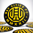 Bay Cities FC logo sticker on a black circular background with yellow text and design.