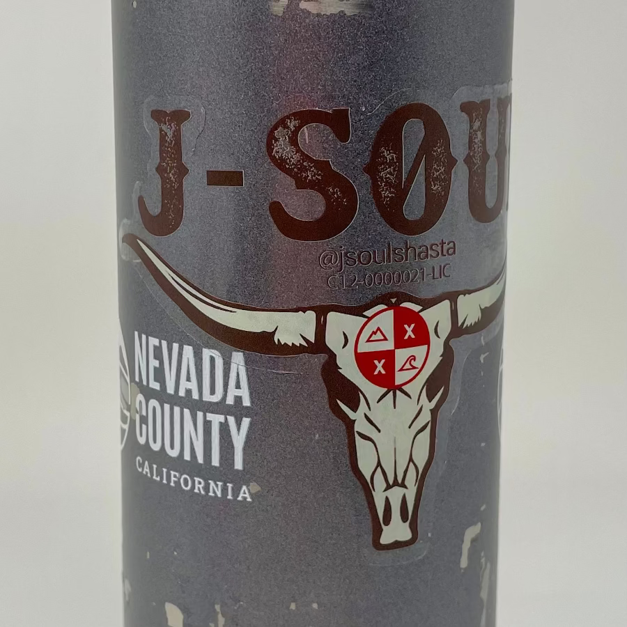 Close-up of a clear sticker on a gray water bottle, featuring a custom longhorn skull design with red and brown artwork and a transparent background.