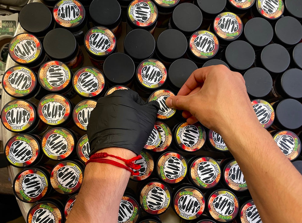 Custom product labels being hand-applied to jars for retail packaging.