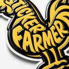Close-up of a die-cut Sticker Farmer rooster sticker with bold yellow lettering and thick, highly raised 3-pass spot UV coating on the black areas.